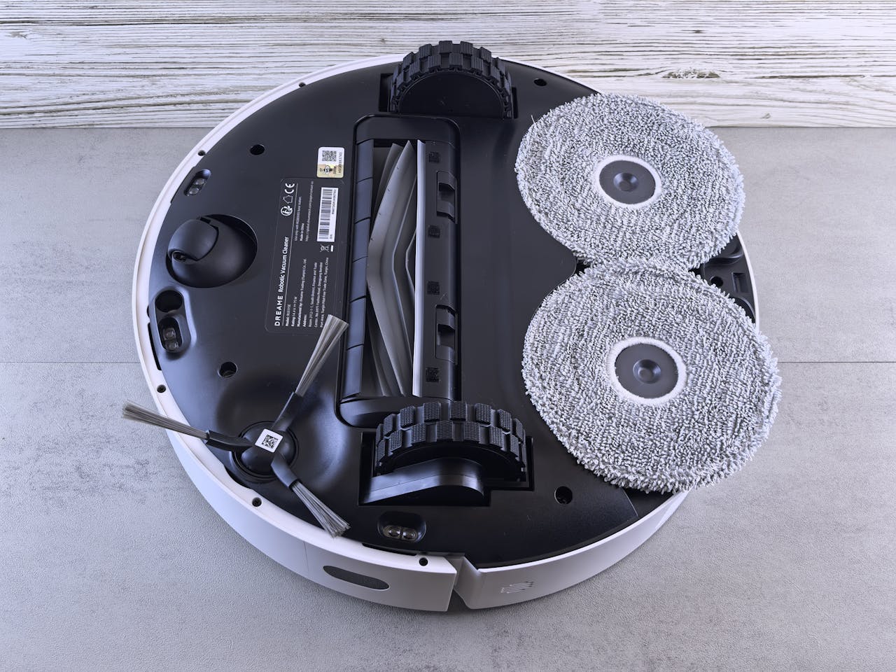Detailed view of a robotic vacuum cleaners underside showing brushes and wheels.
